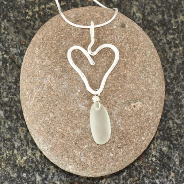 Guernsey sea glass pendant suspended below a sterling silver heart.