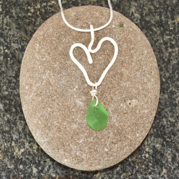 Guernsey sea glass pendant suspended below a sterling silver heart.