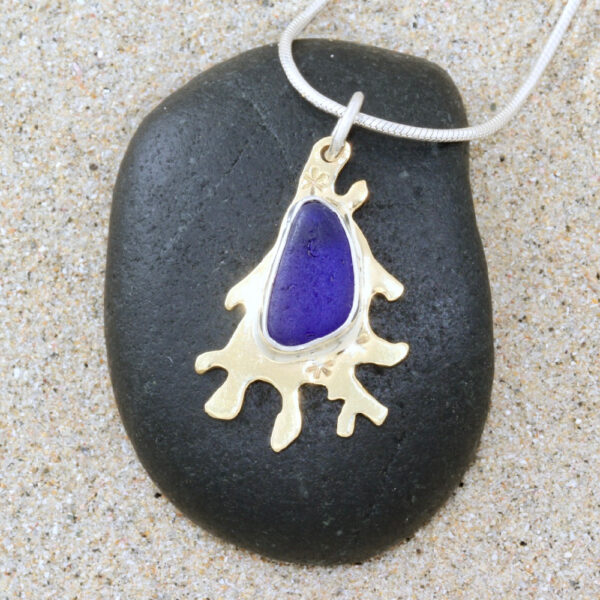 This 'vraic' (seaweed) style pendant is made from brass with sterling silver bezelled sea glass and barnacle detailing inspired by Guernsey's wonderful rockpools.